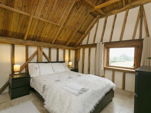 Chilsham Barn في Herstmonceux: غرفة نوم مع سرير في غرفة مع نافذة