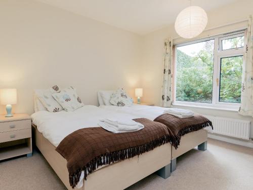 a white bedroom with a large bed with a window at Gorwel Glas in Fishguard