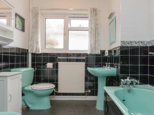 a bathroom with a blue toilet and a sink and a tub at Gorwel Glas in Fishguard