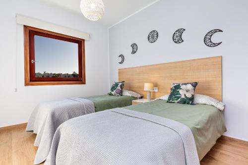 two beds in a white room with a window at Sea Moon Lanzarote in Playa Blanca