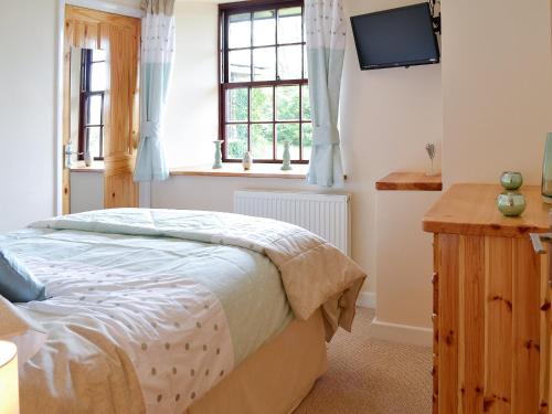 North MoltonにあるBridge House - Ukc1340のベッドルーム1室(ベッド1台、壁にテレビ付)