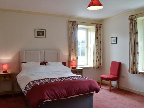 um quarto com uma cama grande e uma cadeira vermelha em Bonshawside Farmhouse em Kirtlebridge