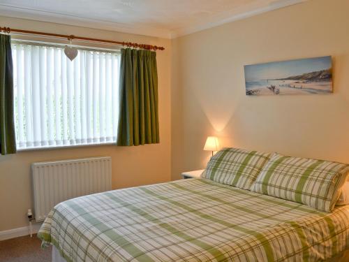 a bedroom with a bed with a plaid bedspread at Sea Breeze Bungalow in Sutton on Sea