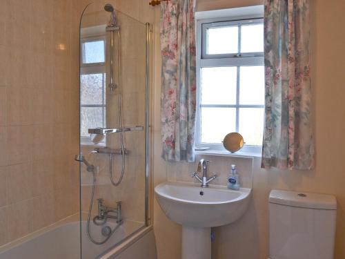 a bathroom with a sink and a shower and a toilet at Sea Breeze Bungalow in Sutton on Sea
