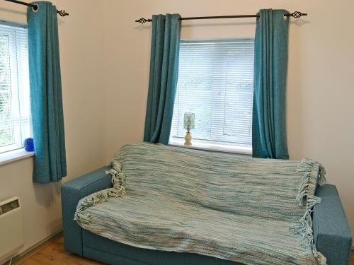 a bedroom with a bed with blue curtains and a window at The Pocker Watch in Chideock