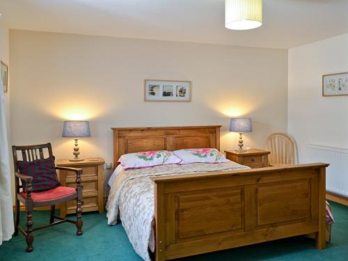 a bedroom with a bed and two chairs and two lamps at Nellys Cottage in Lanehead