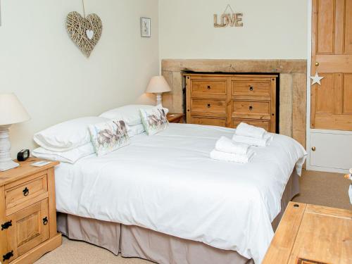 a bedroom with a large white bed and a wooden dresser at Harrys Den in Alnwick