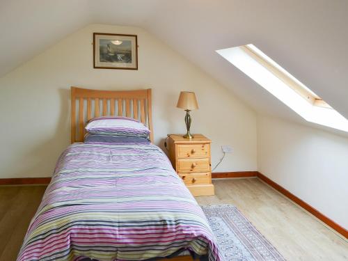 a bedroom with a bed and a lamp on a dresser at Broomstick Cottage in Elsdon
