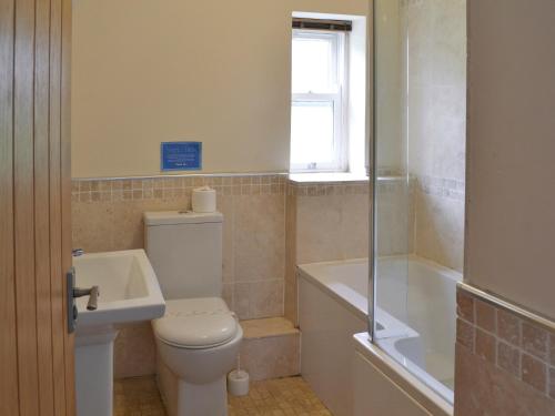 a bathroom with a toilet and a tub and a sink at Raby Cottage-27764 in Wolsingham