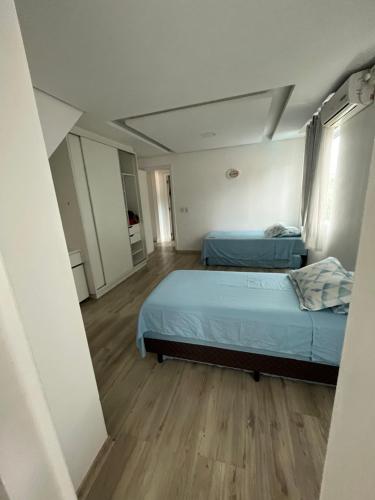 a bedroom with two beds and a wooden floor at Casa com Piscina in Florianópolis