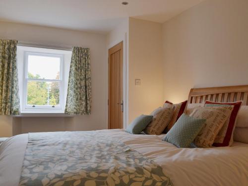 a bedroom with a large bed with a window at Well Cottage in Ceres