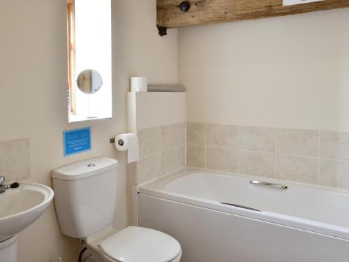 a bathroom with a tub and a toilet and a sink at Blackbird Cottage - 25116 in Flamborough