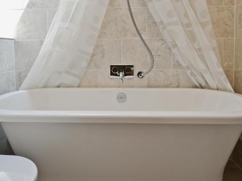uma banheira branca na casa de banho com WC em The Coach House em Tenbury