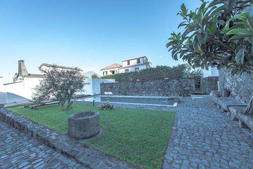 un jardín con un camino de piedra y una casa en Casa do Brasão, en Lajes do Pico