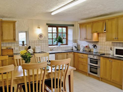 a kitchen with wooden cabinets and a table with chairs at Cider Cottage - E5576 in Warkleigh