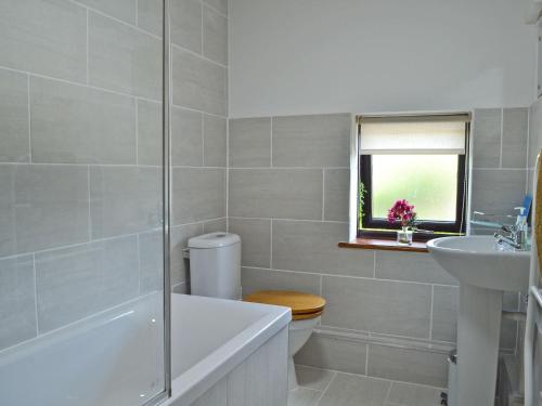 a bathroom with a tub and a toilet and a sink at Stable Cottage in Ticehurst