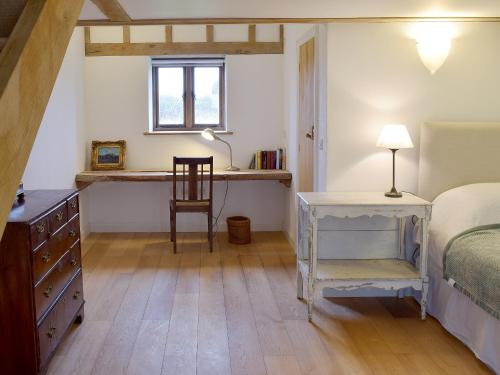 um quarto com uma cama, uma secretária e uma cadeira em Low Farm Barn em Laxfield