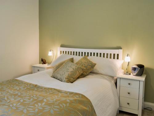 a bedroom with a white bed with two night stands at Cottage On The Green in York