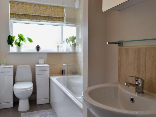 a bathroom with a toilet and a sink and a tub at Cottage On The Green in York