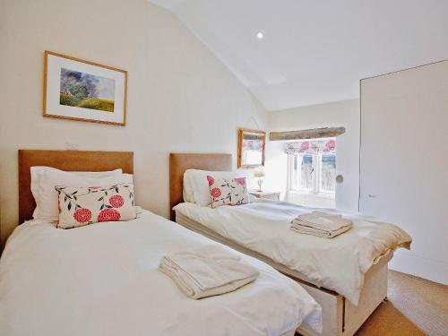 two twin beds in a room with a window at The Mill House-tt3 in Warleggan