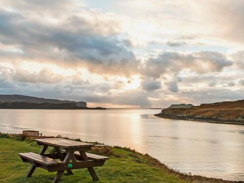 a picnic table sitting next to a body of water at Seascape in Staffin