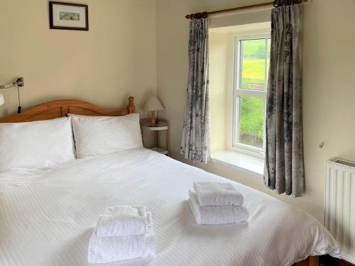 a bedroom with a white bed with towels on it at Riverside Cottage in Horton in Ribblesdale