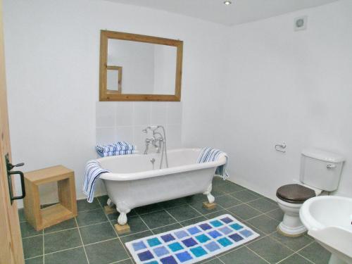 ein Badezimmer mit einer Badewanne, einem WC und einem Spiegel in der Unterkunft What A Beauty - Thr in Tresmeer