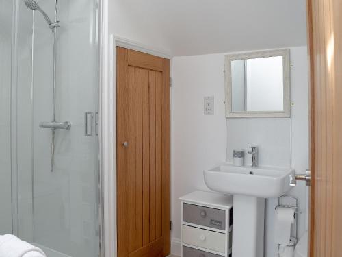 a white bathroom with a sink and a shower at Derbys Loft in Beccles
