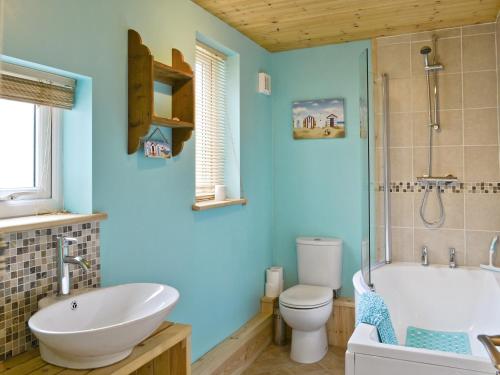 baño con paredes azules, lavabo y aseo en Eastwyn en Winterton-on-Sea