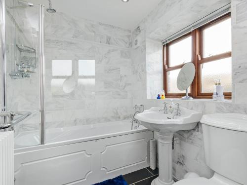 a white bathroom with a tub and a sink at Lillegarth in Bradwell