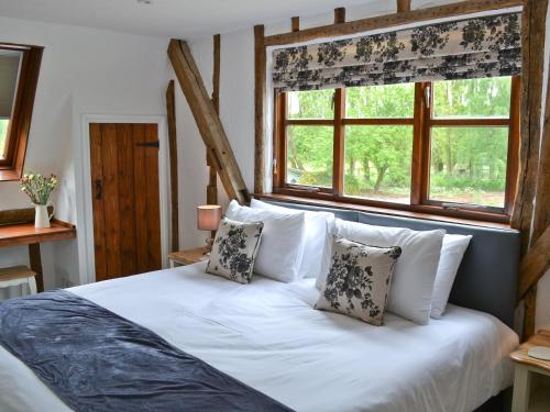 a bedroom with a white bed with pillows and a window at The Old Stables in Rickinghall