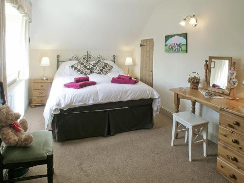 a bedroom with a large bed with pink pillows at Two Bridge Cottage in Winsham