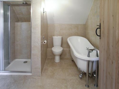 a bathroom with a tub and a toilet and a sink at Two Bridge Cottage in Winsham
