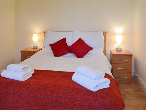 a bedroom with a bed with red pillows and two lamps at The Haybarn in High Halstow