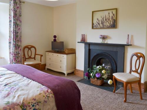 a bedroom with a fireplace and a bed and chairs at North Coombe Farm in Upton