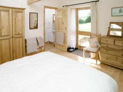 a bedroom with a white bed and a window at Peartree Cottage in St. Mellion