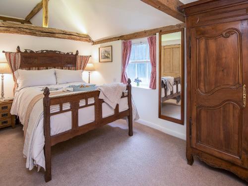 a bedroom with a wooden bed and a mirror at Pheasants Hill Old Byre in Hambleden