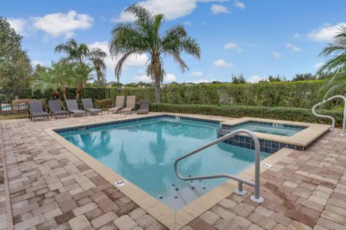 a swimming pool with chairs and trees in a yard at Huge 10 BDR Family House with Arcades and Free Pool Heat Near Disney in Orlando