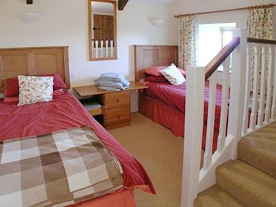 Saint Martins GreenにあるJemima Cottageのベッドルーム1室(ベッド2台、デスク、階段付)