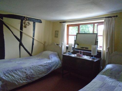 a bedroom with two beds and a desk with a mirror at Whipple Tree Cottage in Cratfield