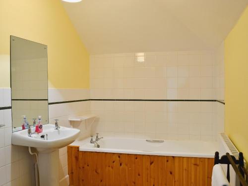 La salle de bains est pourvue d'un lavabo et d'une baignoire. dans l'établissement Farrer Cottage, à Straiton