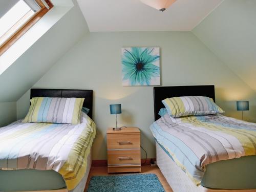 a bedroom with two beds and a dresser and a window at Lochview in Milovaig