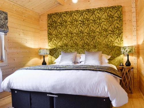 a bedroom with a large bed with a wooden wall at Ty Pren in Dyffryn