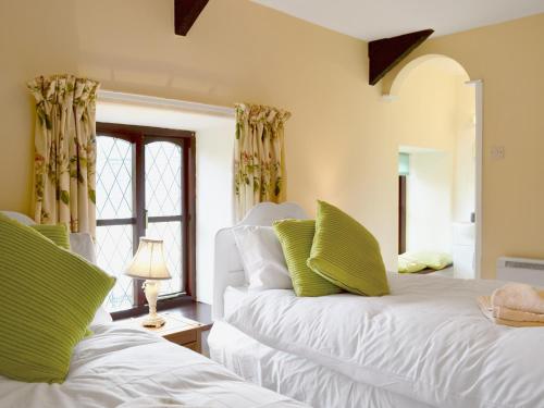 a bedroom with two white beds with green pillows at Bwthyn in New Quay