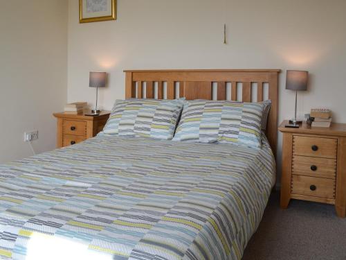 Poplar Bungalow في Lyng: غرفة نوم مع سرير مع مواقف ليلتين ومصباحين