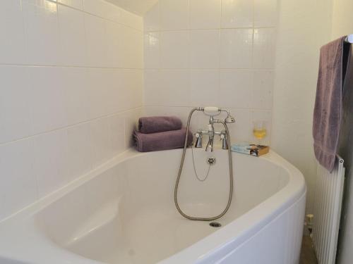 a white bath tub in a bathroom with a purple towel at Willow Cottage in Woolfardisworthy