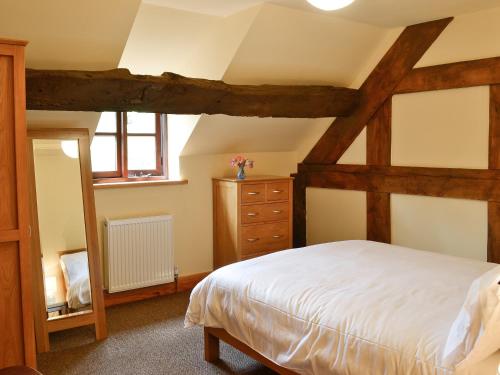 a bedroom with a bed and a dresser in a room at Mill Cottage in Peterchurch