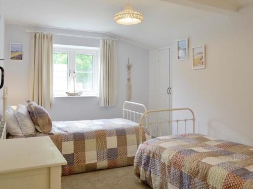 een slaapkamer met 2 bedden en een raam bij Little Warham Cottage - Ukc1986 in Beaford