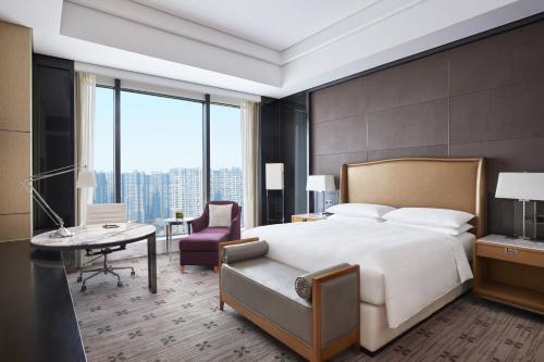 a bedroom with a large bed and a desk and chair at Zhuzhou Marriott Hotel in Zhuzhou
