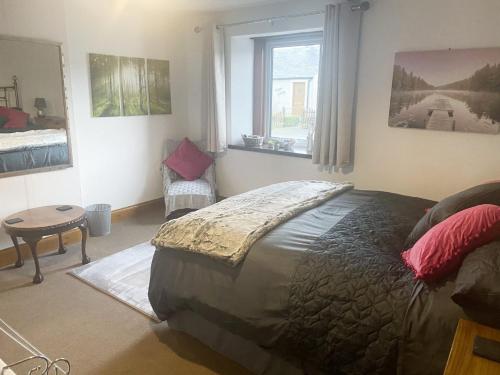 a bedroom with a large bed and a window at Iona Cottage in Clarencefield